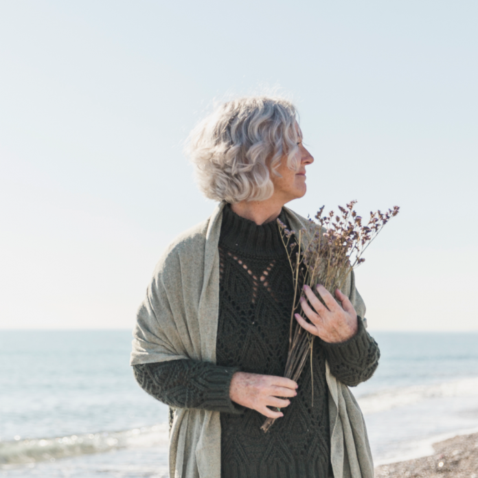 a women holding flowers on a beach